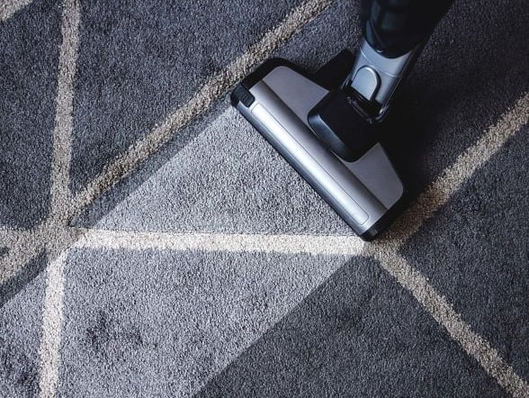 A vacuum machine cleaning a dirty navy carpet